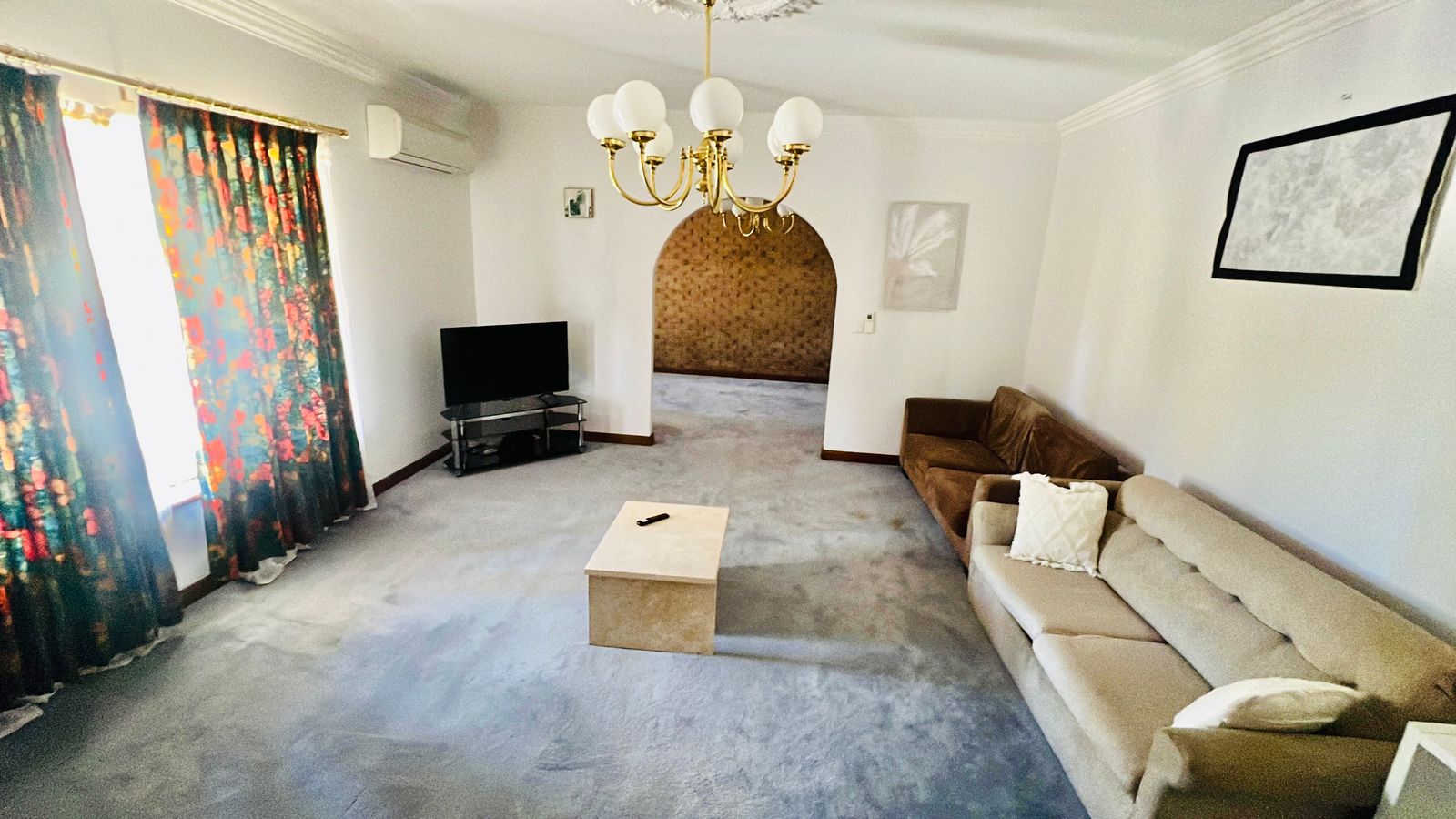 A large carpeted lounge room in an Evora Care home, with sofas and a television