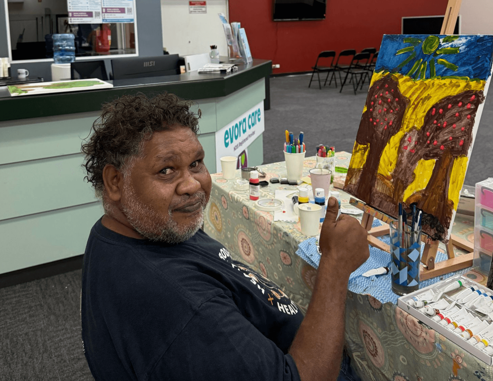 A participant painting a bright desert landscape at the Evora Care Activity Centre