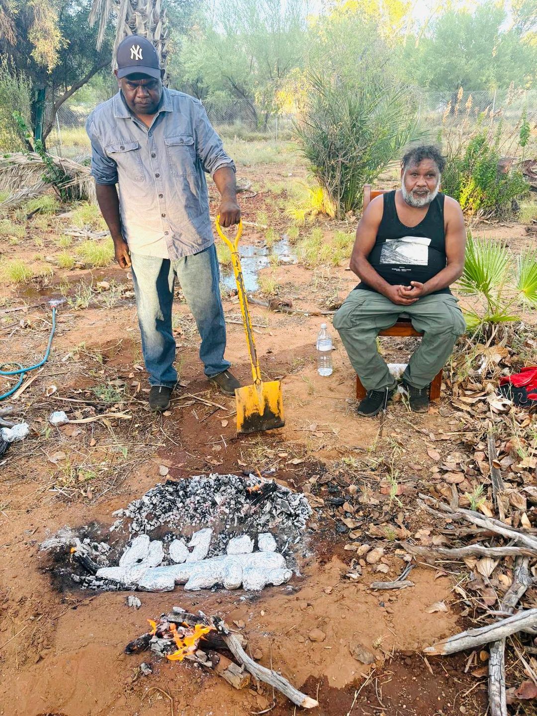 Community members cooking in a ground oven on country near Alice Springs